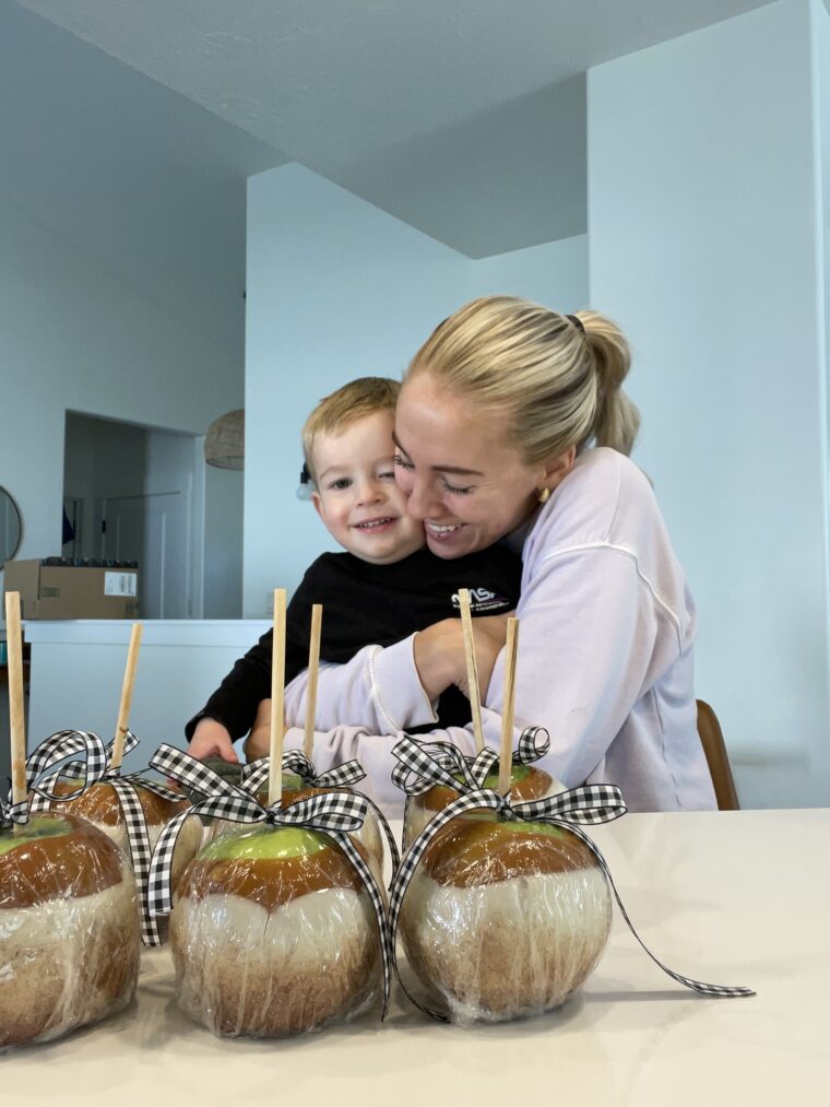 Mom holding baby with carmel apples wrapped in front of them
