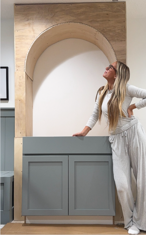 Sarah is looking up at the wooden arch she build at home.